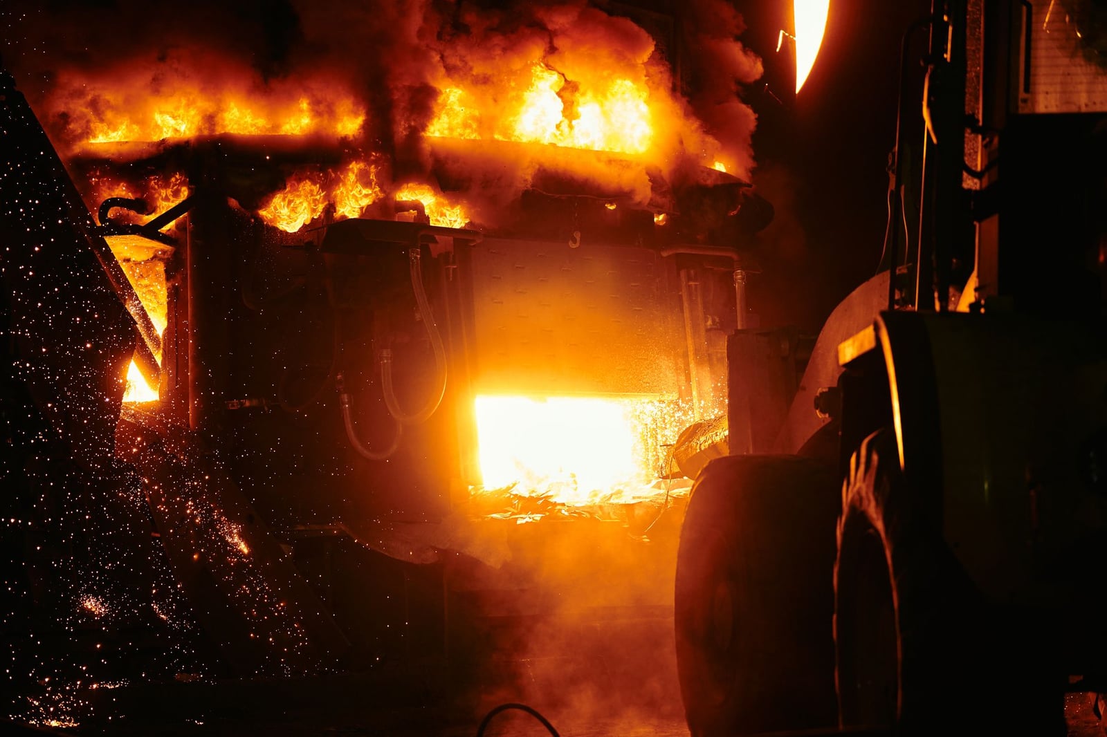 Primer plano de un horno en llamas en un entorno industrial que emite llamas intensas y chispas.