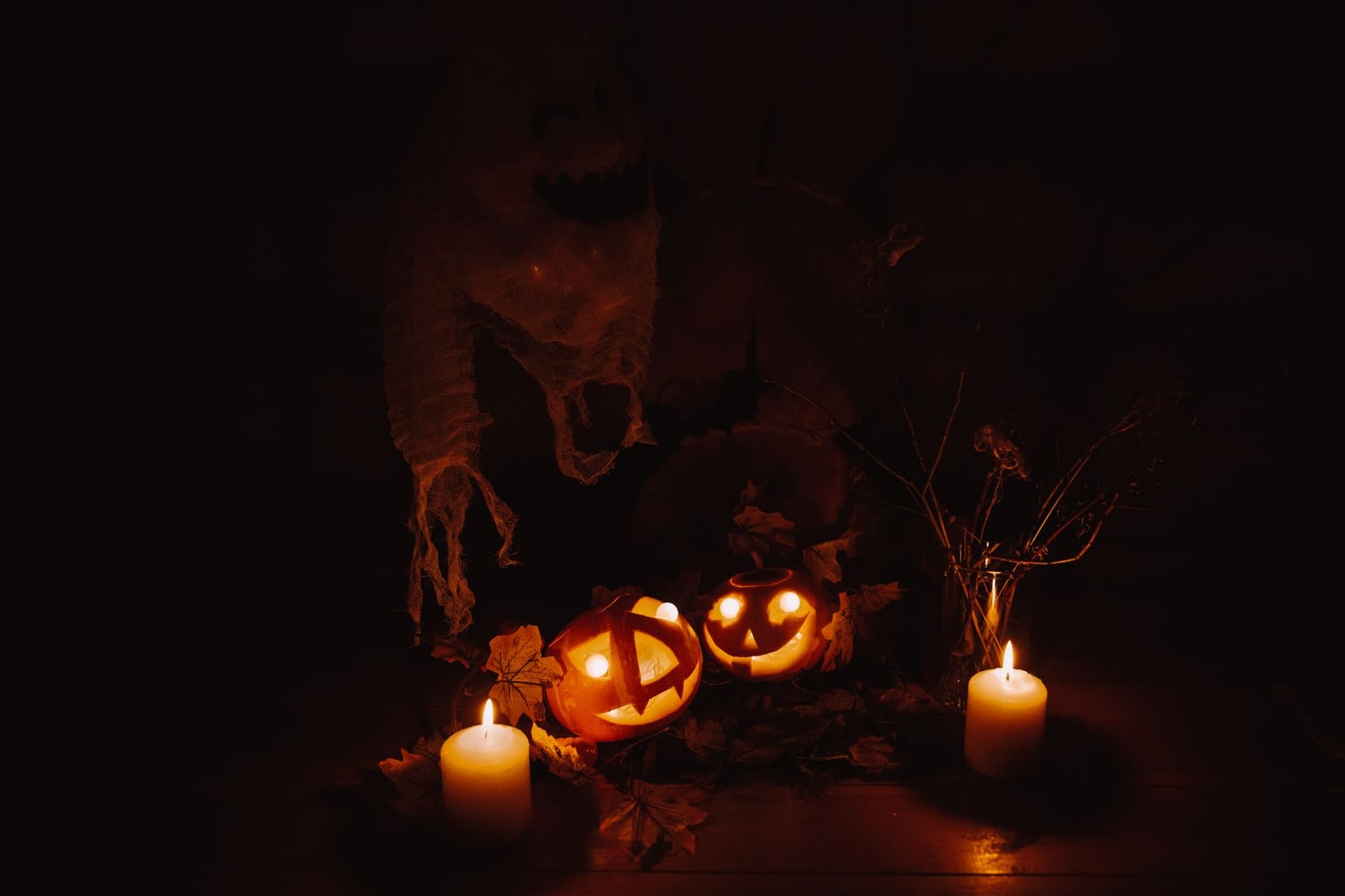 Exhibición de Halloween tenebrosa con calabazas brillantes y velas que proyectan sombras inquietantes.