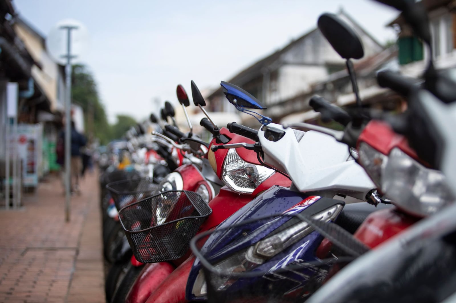 Acercamiento a múltiples scooters estacionadas en una calle de la ciudad lluviosa. Escena de transporte urbano.