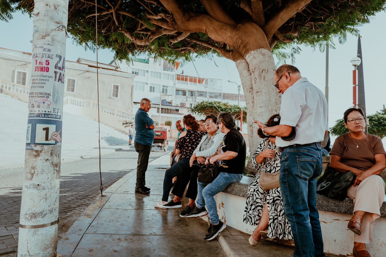 Las personas se reúnen bajo un árbol en Pacasmayo, Perú, disfrutando de un día soleado.