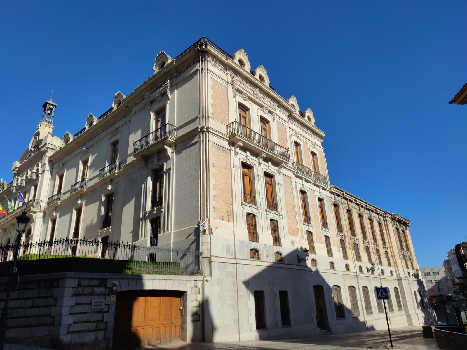 Fachada elegante de palacio en Jaén, España, que muestra un estilo arquitectónico clásico bajo un cielo azul claro.