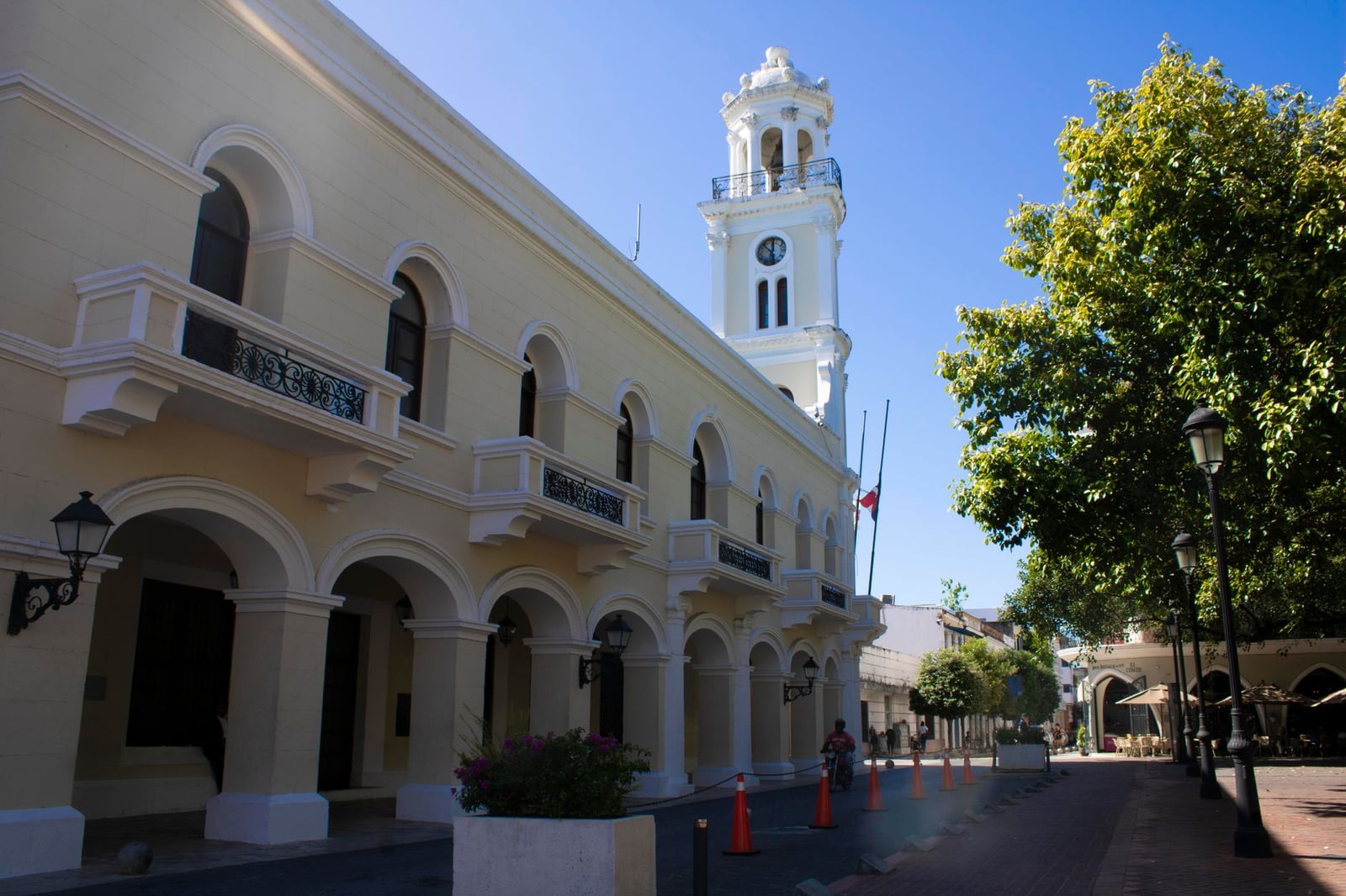 Arquitectura colonial clásica con ventanas arqueadas y una torre del reloj, bajo un cielo azul brillante.