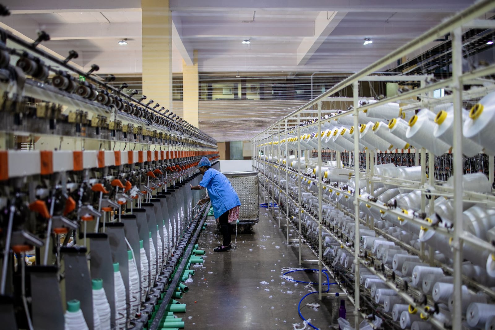 Un trabajador textil manejando maquinaria en un entorno de fábrica moderna.