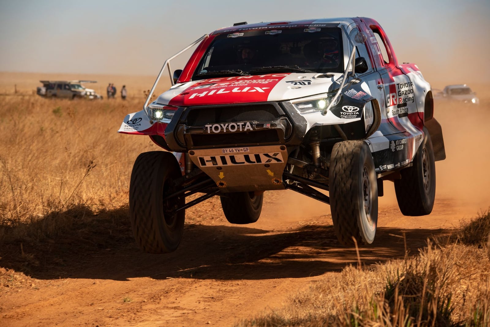 Camión de carreras todoterreno a alta velocidad saltando sobre pista de tierra durante una competición de rally.