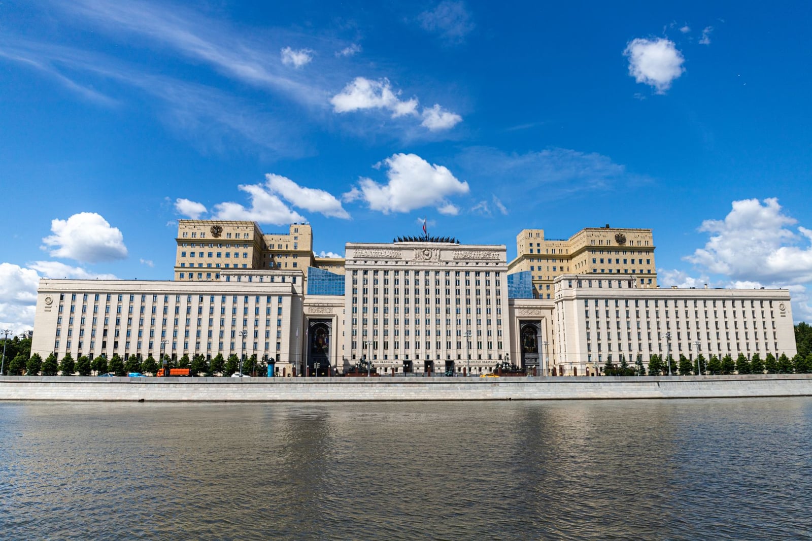 Un majestuoso edificio frente al río capturado en un día soleado con cielos azules claros.