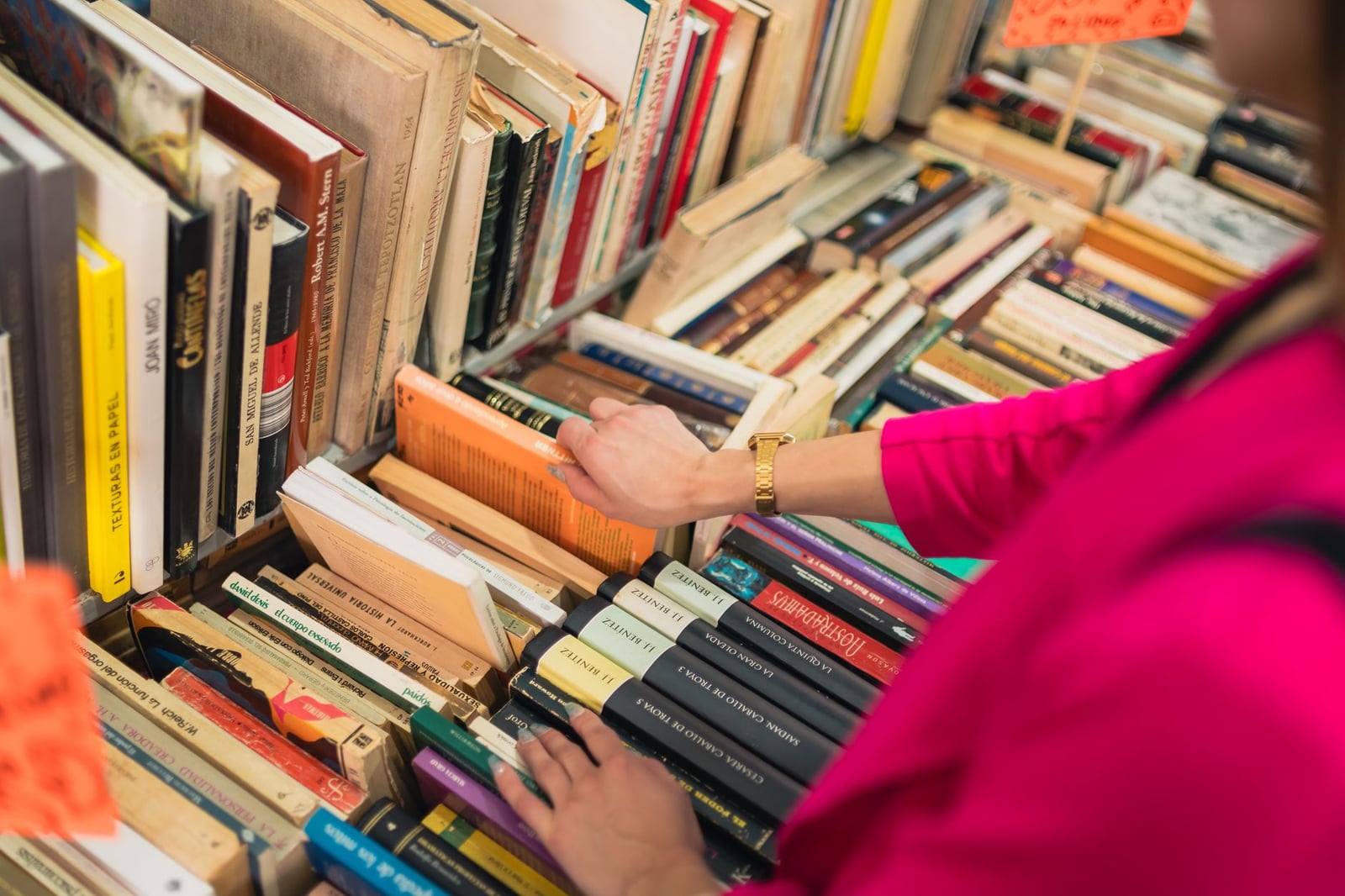 Una persona hojeando libros coloridos en una encantadora librería en la Ciudad de México, enfatizando la cultura y el conocimiento.