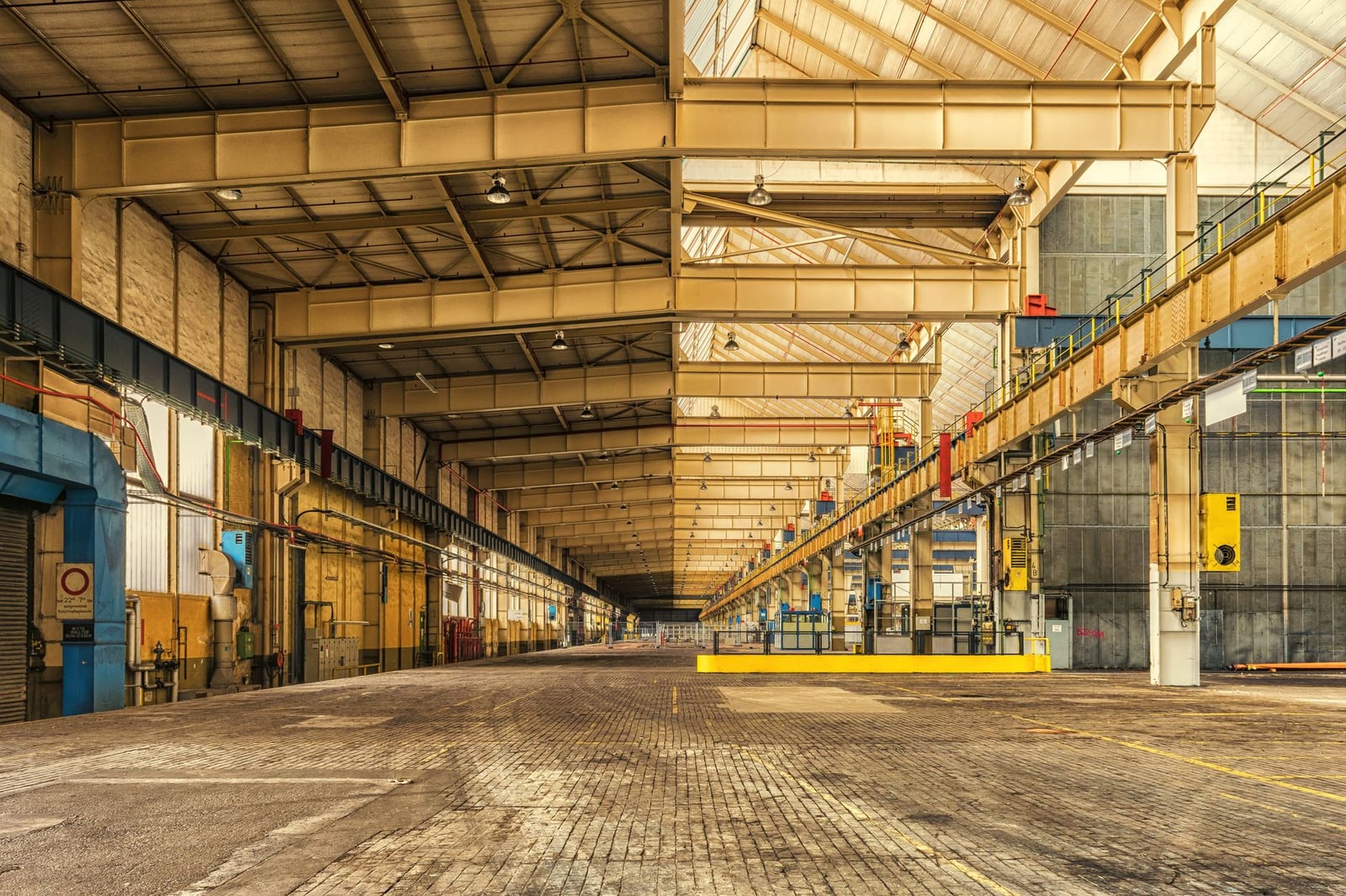 Interior expansivo de un almacén industrial que muestra vigas de acero, techos altos y amplio espacio.