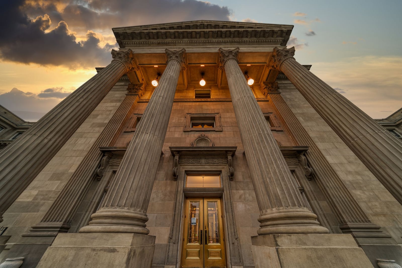 Un gran edificio histórico con columnas altas e iluminado al anochecer, mostrando arquitectura clásica.