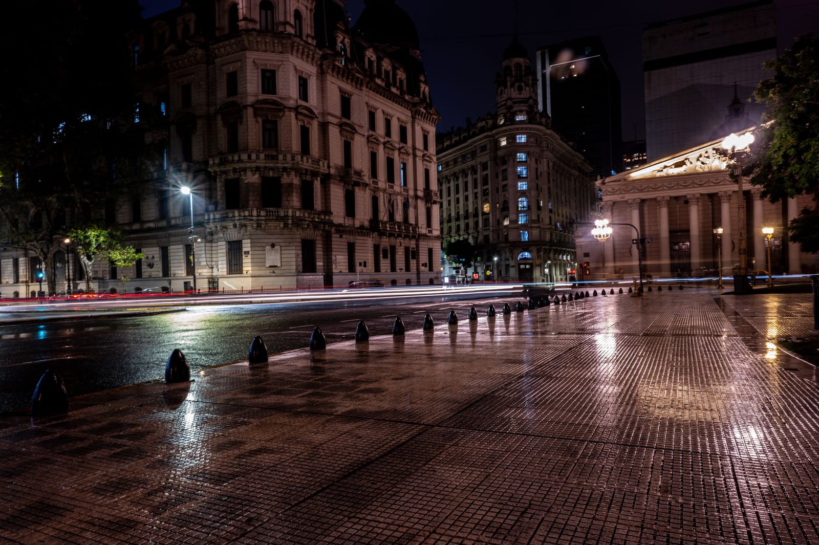 Vista nocturna lluviosa de edificios históricos y calles mojadas en Buenos Aires, Argentina.