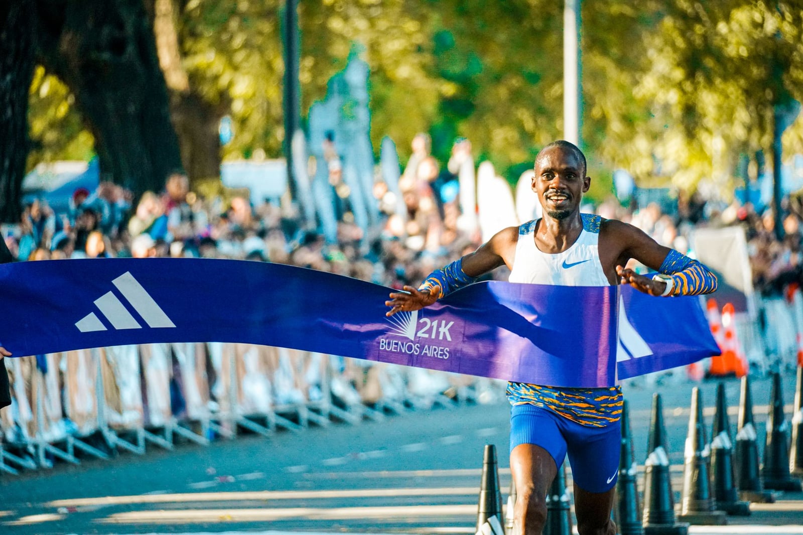 Atleta masculino cruzando la línea de meta en el maratón de Buenos Aires en un animado evento al aire libre.