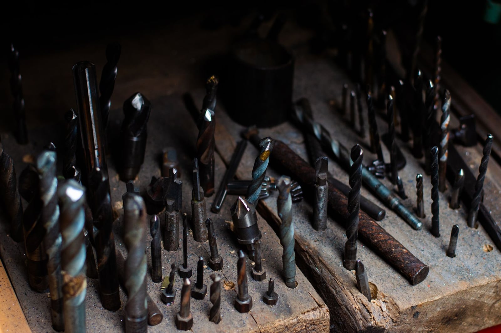 Colección de varias brocas en una tabla de madera, ideal para trabajos en metal y madera.