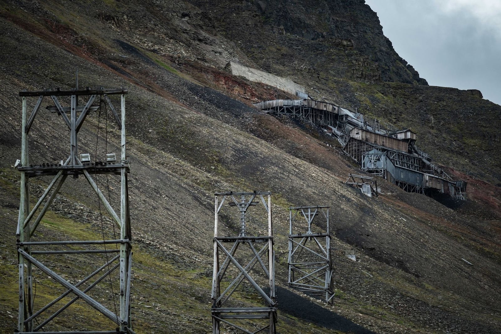 Estructuras mineras antiguas en una empinada ladera montañosa, mostrando la decadencia industrial.