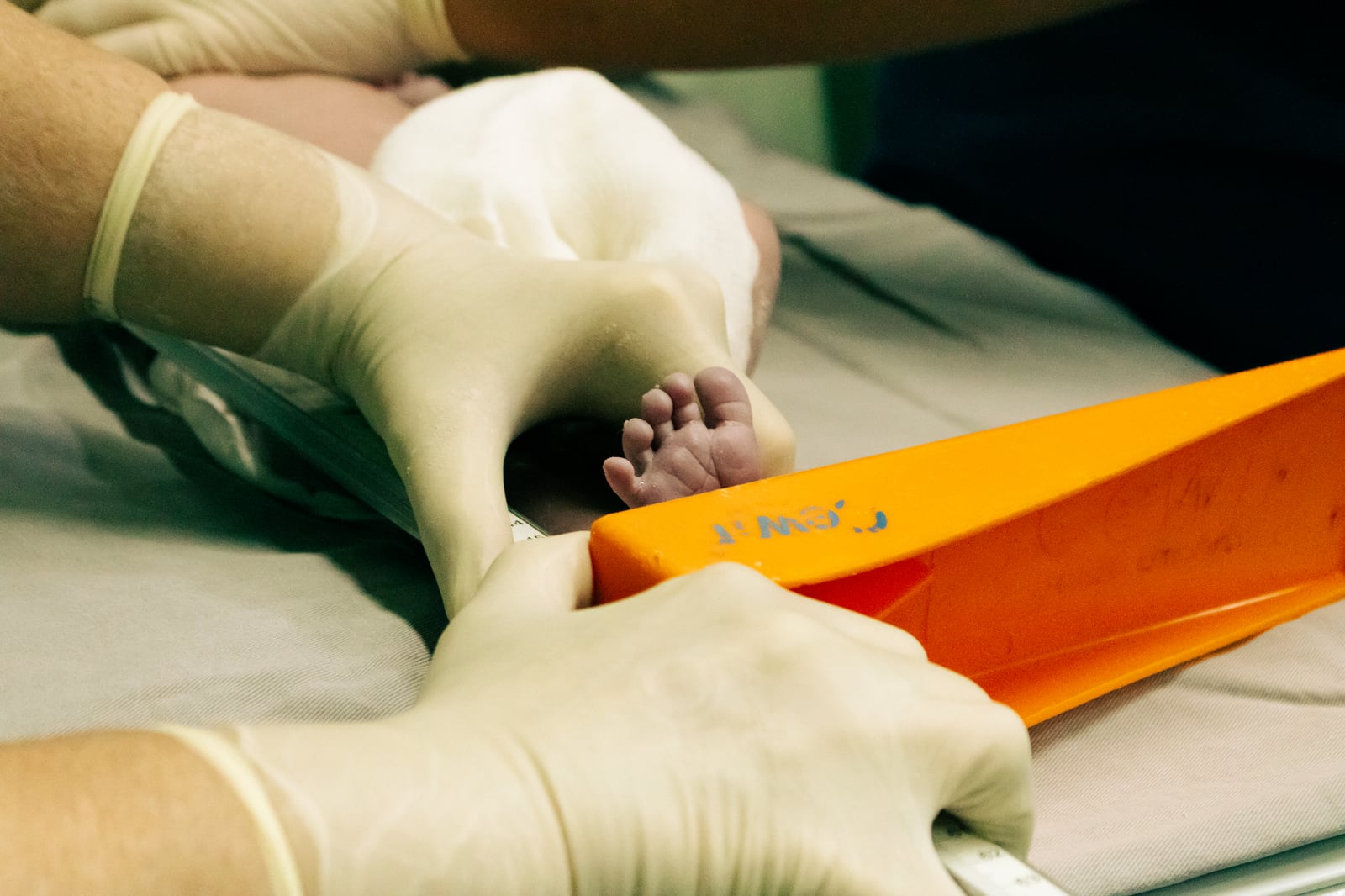 Pie de recién nacido siendo medido por una enfermera en un entorno médico con cuidado.