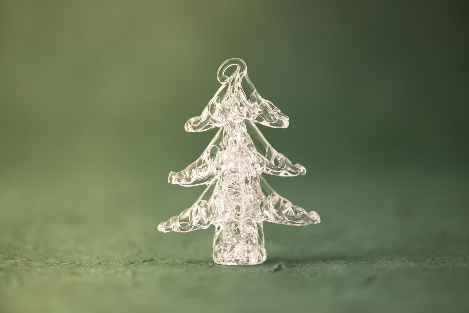 Primer plano de un adorno de árbol de navidad de vidrio transparente sobre un fondo verde festivo.