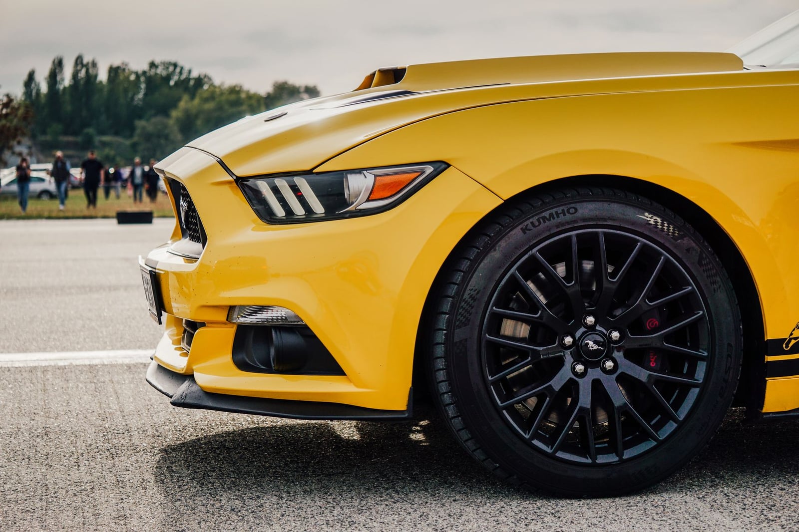 Primer plano dinámico de un elegante coche deportivo amarillo en un día soleado, mostrando su diseño estiloso y neumáticos de alto rendimiento.