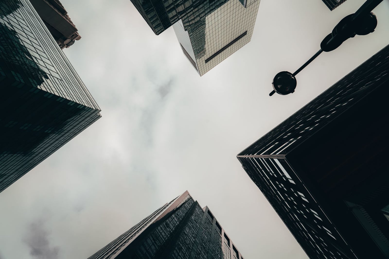 Vista en ángulo bajo de rascacielos y cielo nublado en Nueva York, creando una atmósfera urbana y dramática.