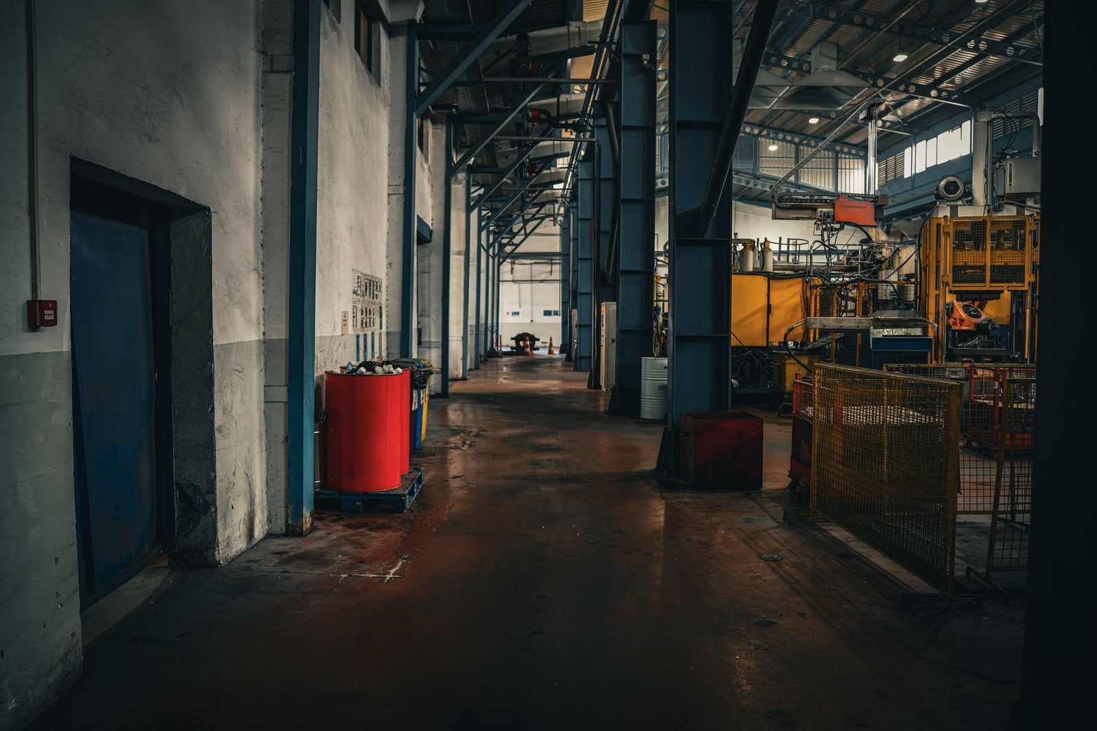 Interior industrial de ambiente sombrío que exhibe amplitud y maquinaria en un entorno de fábrica vacía.