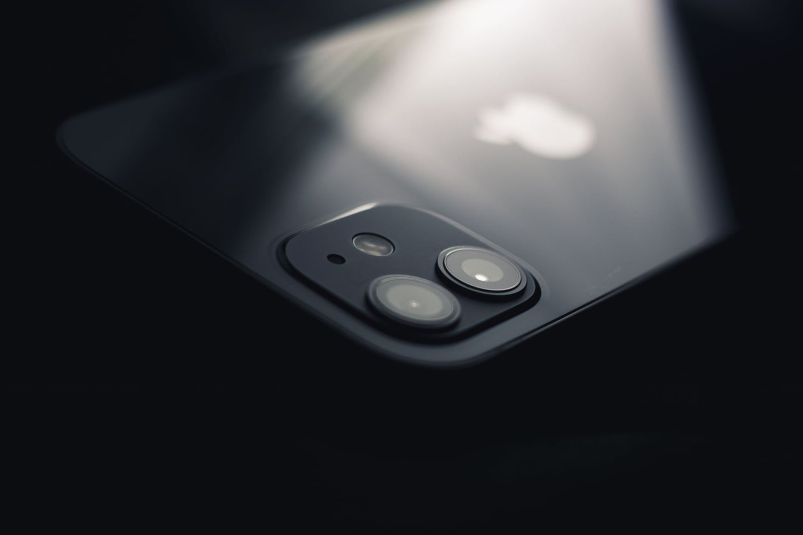 Toma en primer plano de una lente de cámara de smartphone reflejando luz, destacando la tecnología moderna.