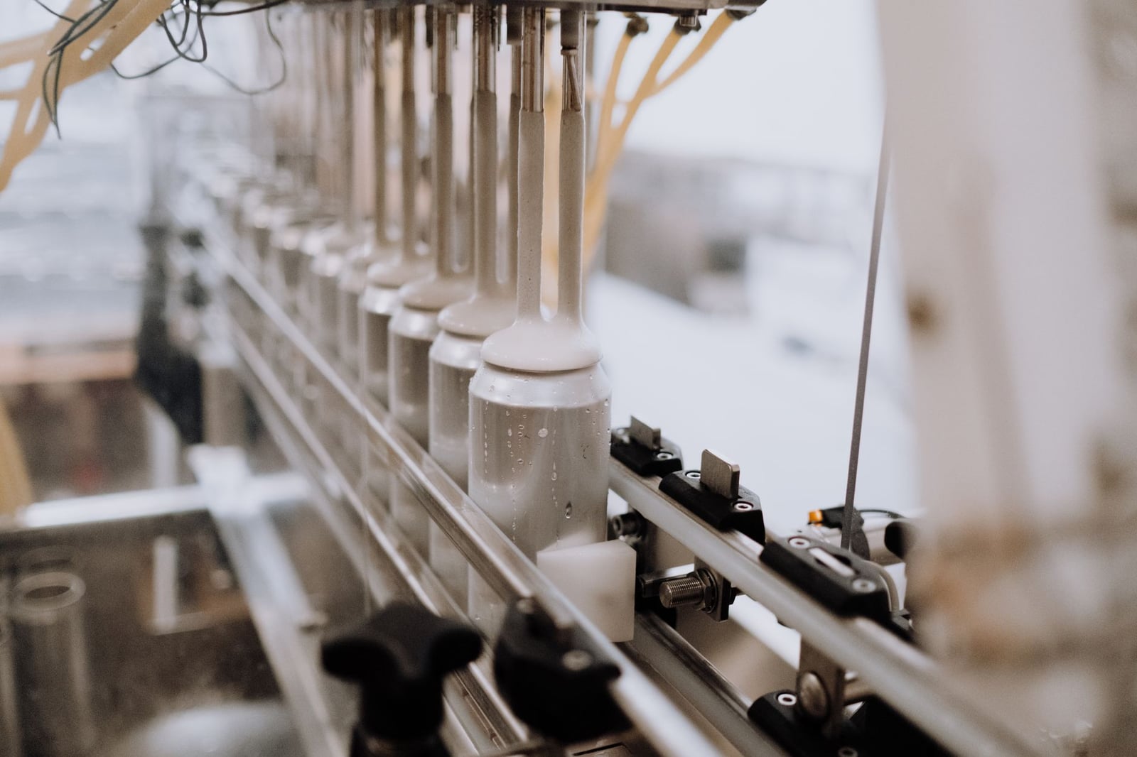 Primer plano de equipos de enlatado automatizados en una cervecería, destacando el proceso de fabricación.
