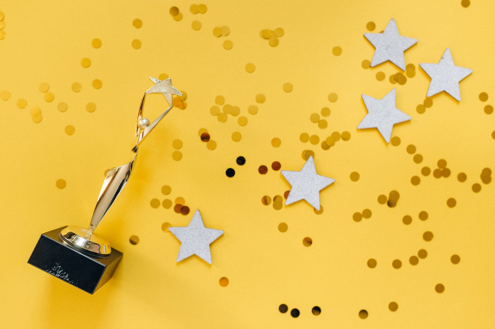 Troféu dorado brillante y estrellas sobre un vibrante fondo amarillo, simbolizando éxito y victoria.