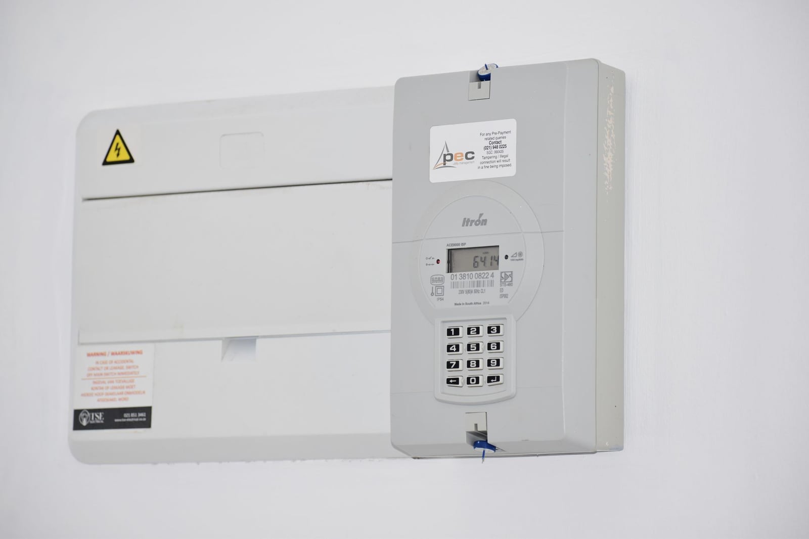 Medidor eléctrico y caja de fusibles en una pared blanca en Ciudad del Cabo, Sudáfrica, para monitoreo de energía o facturación.