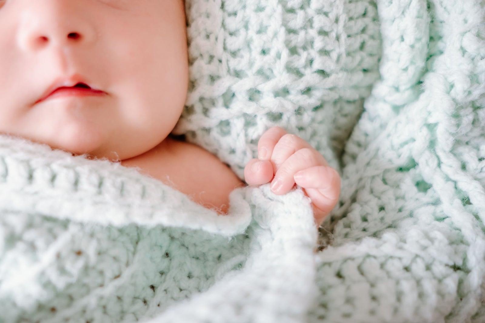 Adorable bebé recién nacido envuelto en una acogedora manta de lana, capturando la inocencia pacífica.