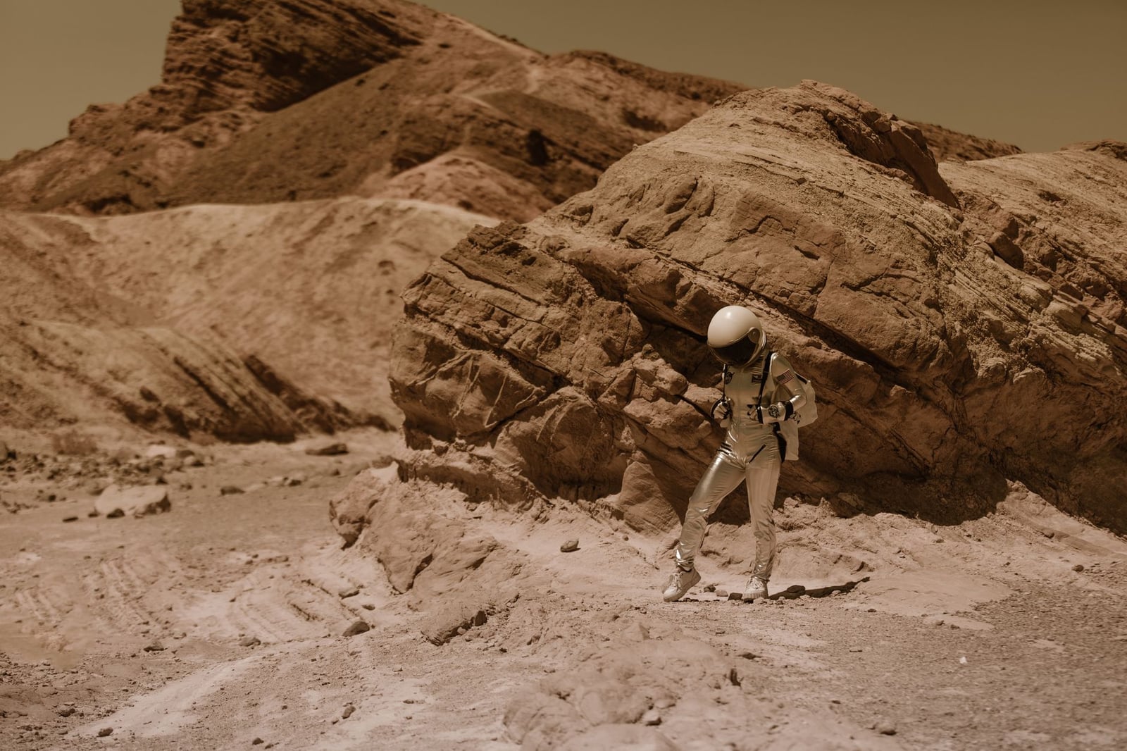 Un astronauta con un traje espacial explora un paisaje desértico árido, que se asemeja a un planeta alienígena.