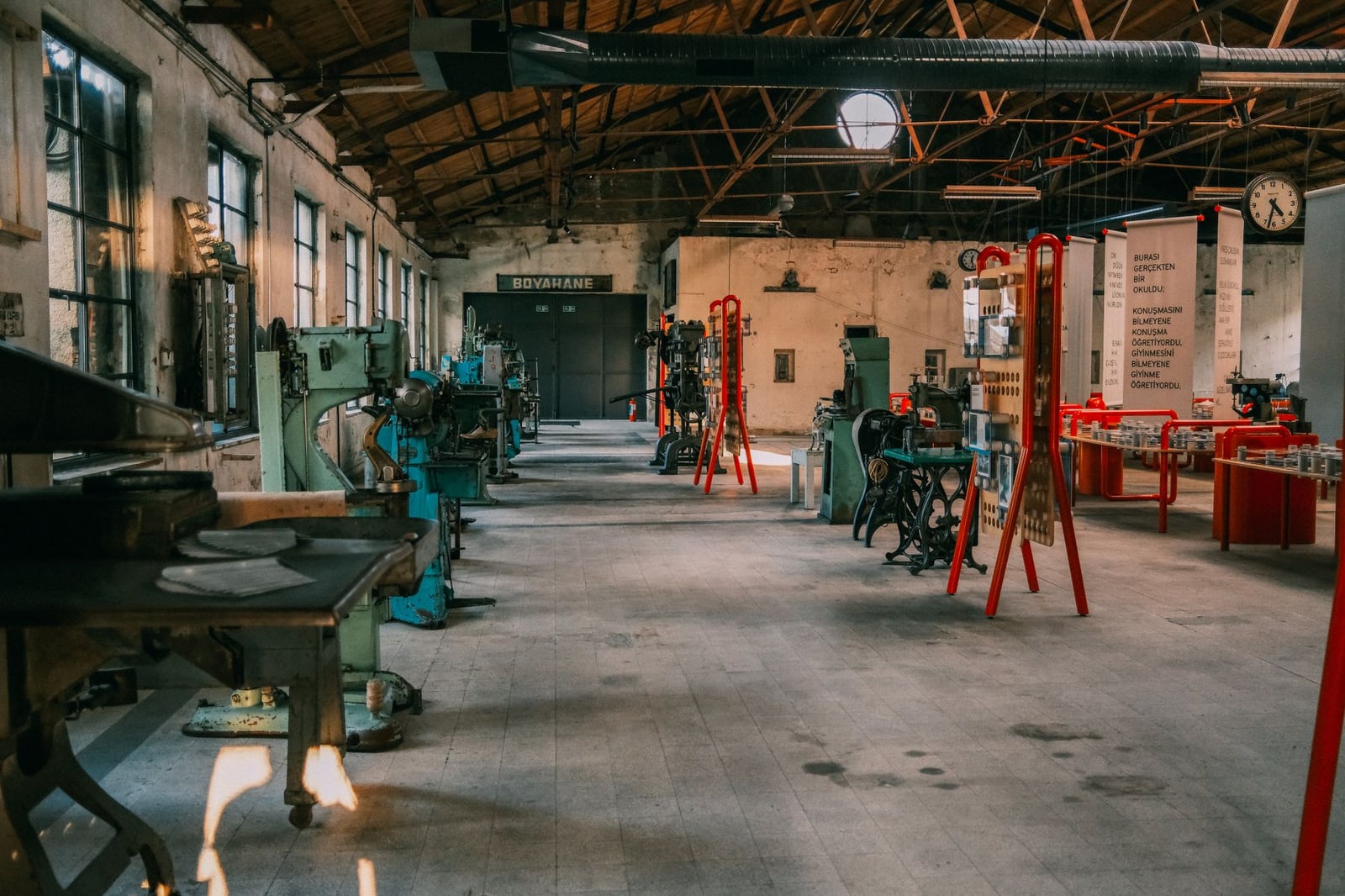 Un taller industrial amplio con maquinaria y herramientas vintage bajo un techo de madera.