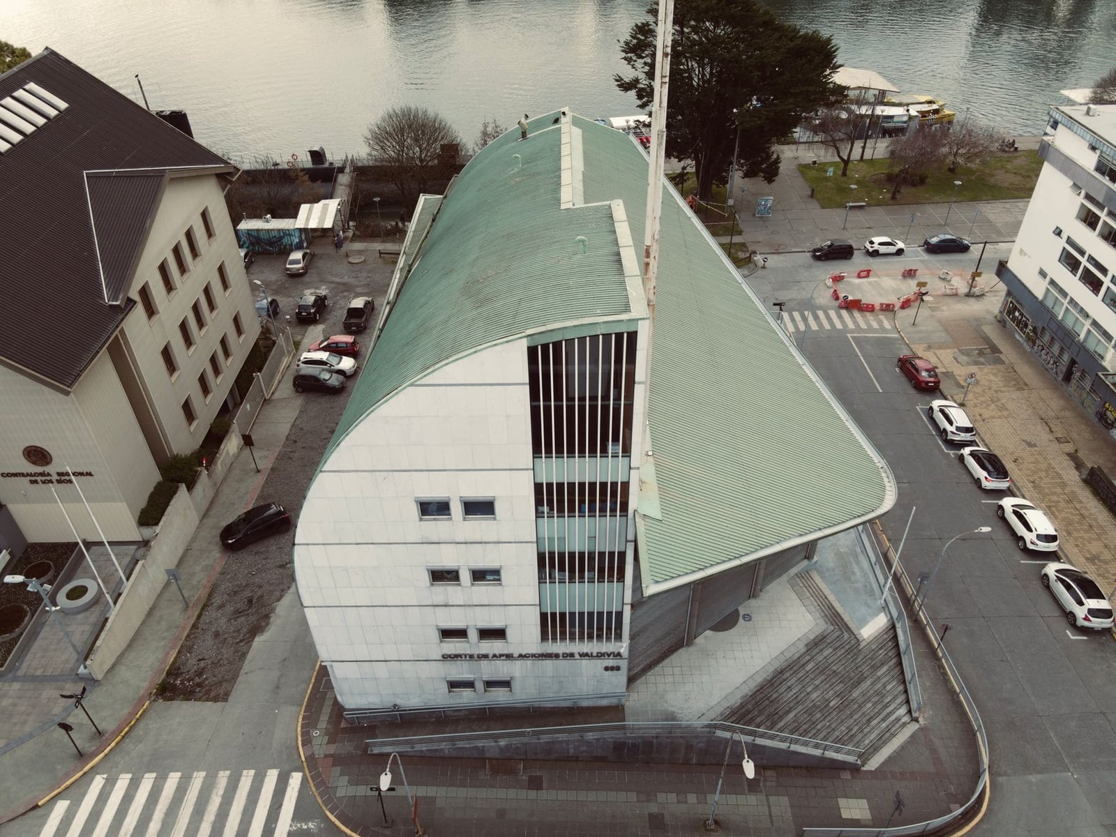 Imagen aérea de un singular edificio de juzgado en Valdivia, Chile, cerca de un río.