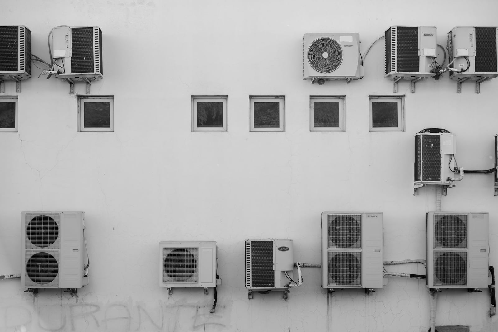 Imagen en blanco y negro de aparatos de aire acondicionado montados en la fachada de un edificio en Córdoba, Argentina.