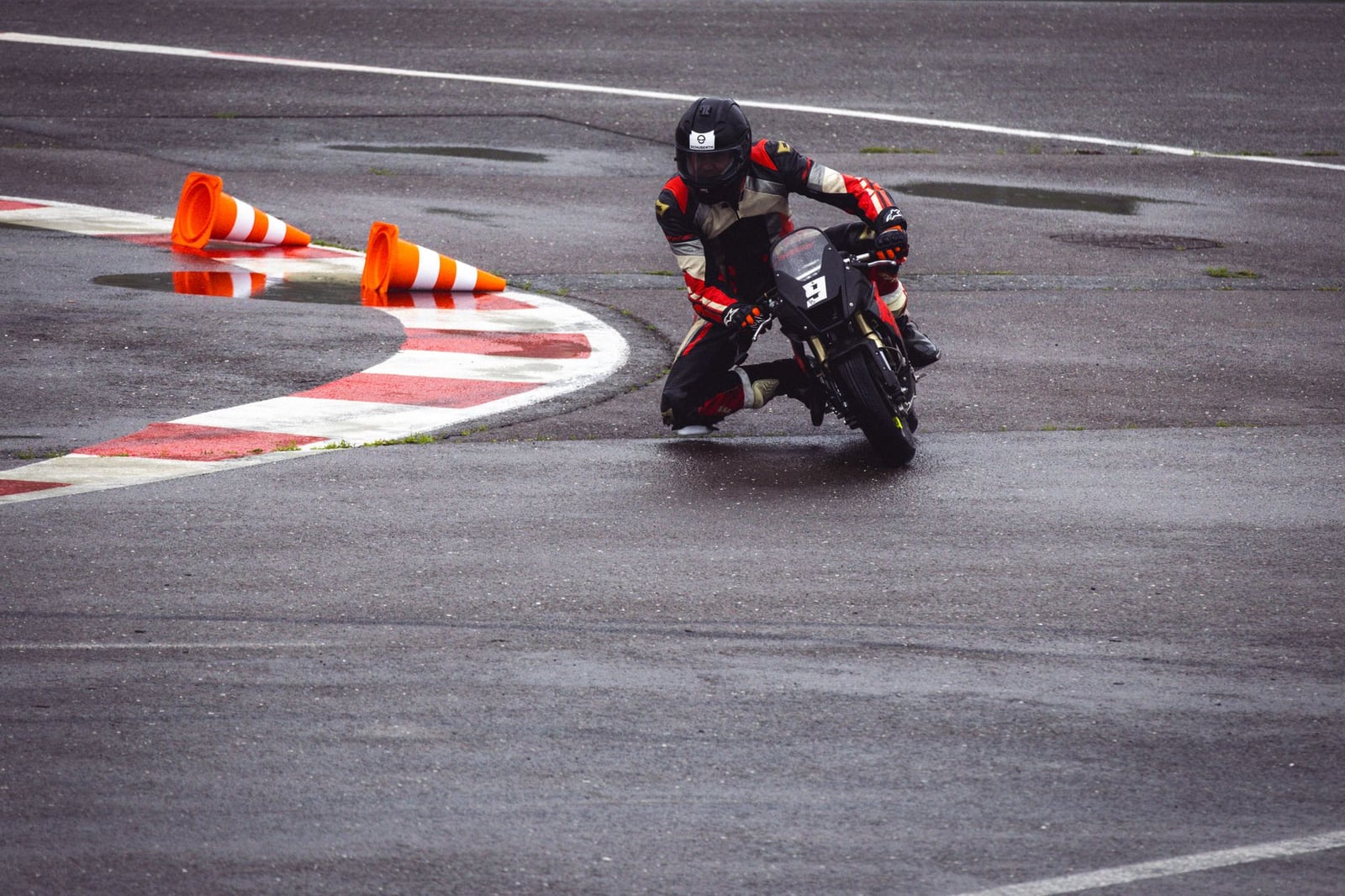 Toma dramática de un motociclista tomando una curva cerrada con destreza en una pista de carreras mojada.