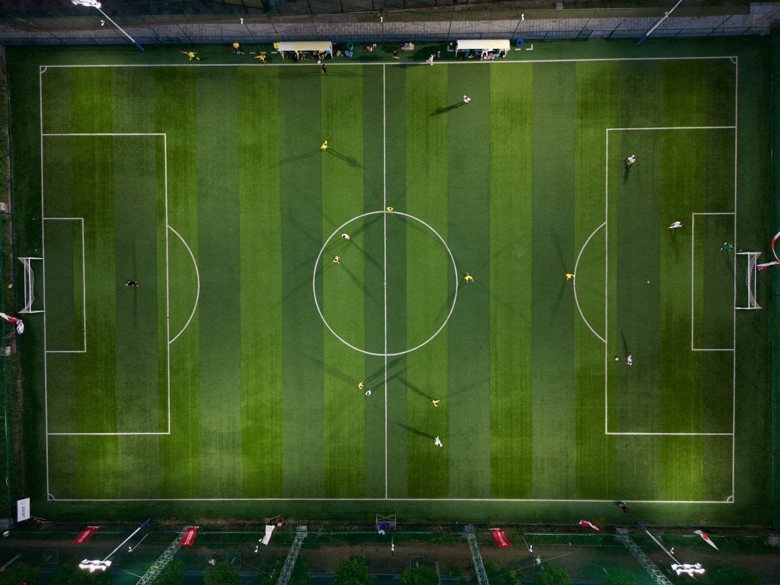Toma aérea dinámica que captura un partido de fútbol en un campo verde vibrante por la noche.