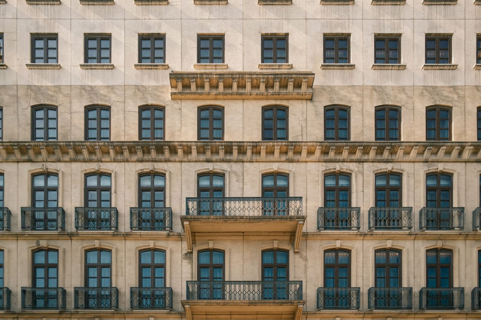 Vista detallada de una fachada urbana clásica con balcones y ventanas a la luz del día.