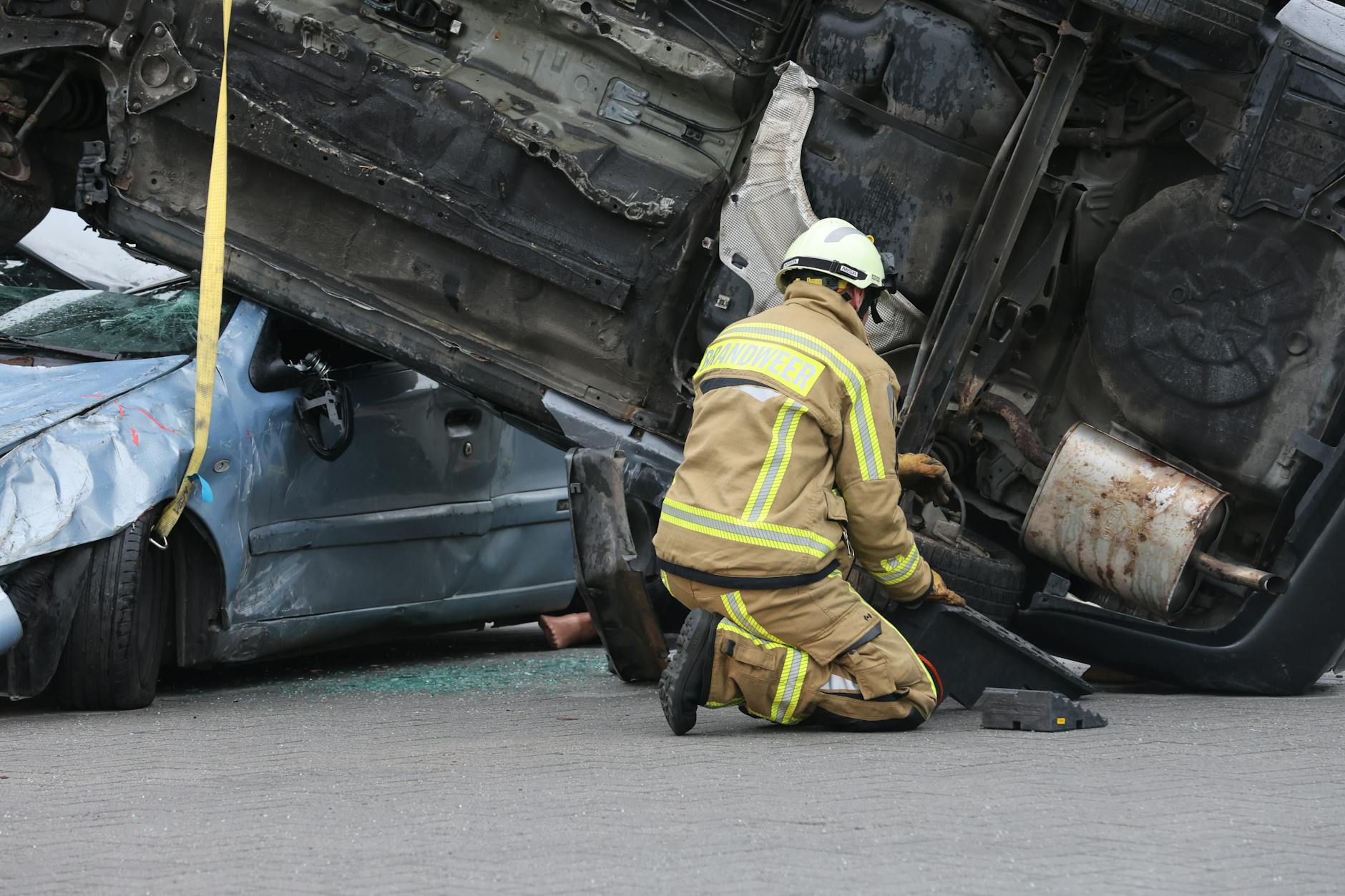 Bombero con equipo ayudando en la escena de un accidente de automóvil volcado, garantizando la seguridad durante la operación de rescate.
