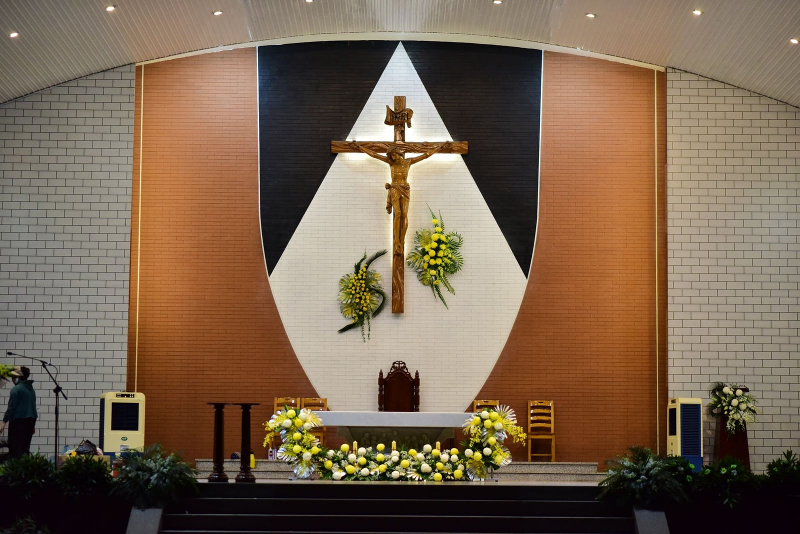Un altar de iglesia con un crucifijo prominente y decoraciones florales, que crea una atmósfera espiritual serena.