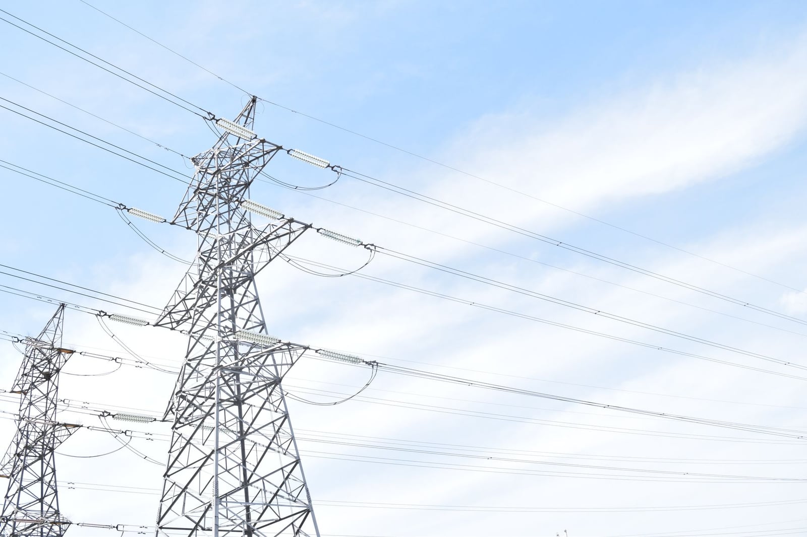 Torres de transmisión de acero contra el cielo azul, destacando la infraestructura de energía y electricidad.