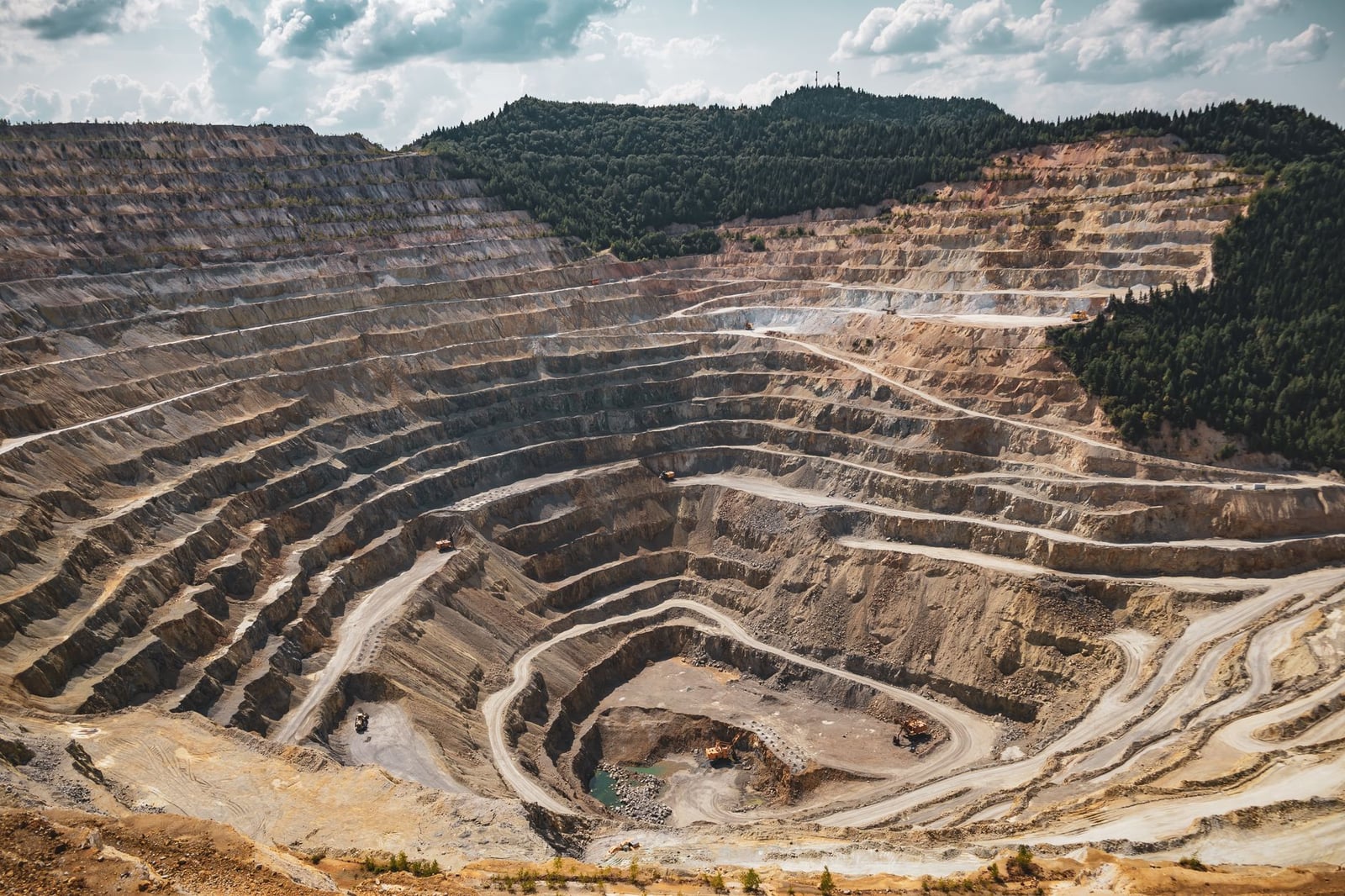 Vista aérea de una gran mina a cielo abierto con excavación en terrazas durante el verano.