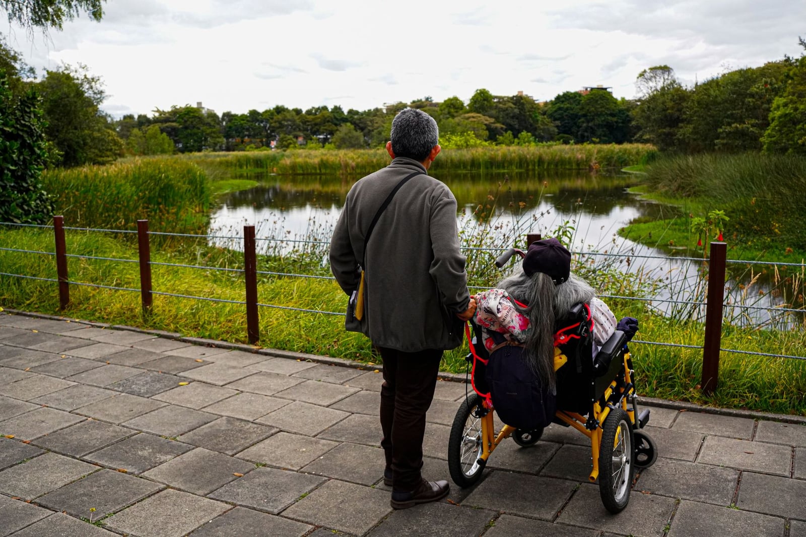 Un momento sereno de una pareja mayor junto a un lago, reflexionando sobre la vida y la belleza natural.