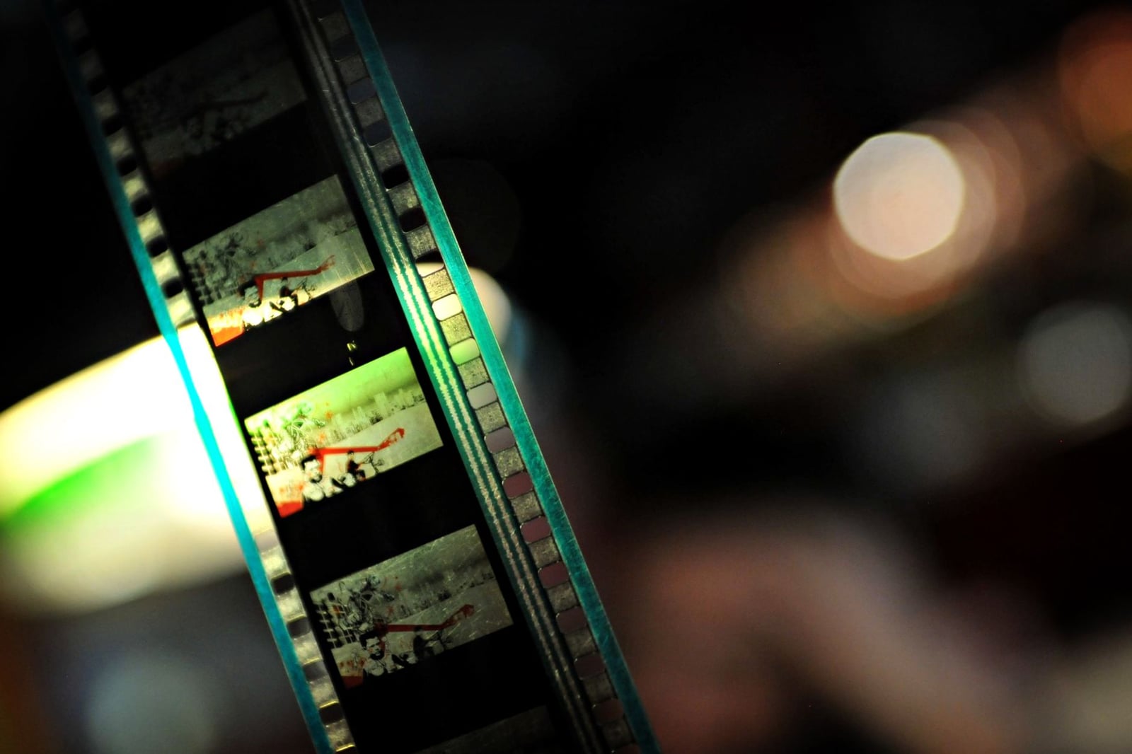 Primer plano detallado de una cinta de film con luces coloridas y bokeh suave de fondo, creando una sensación nostálgica.