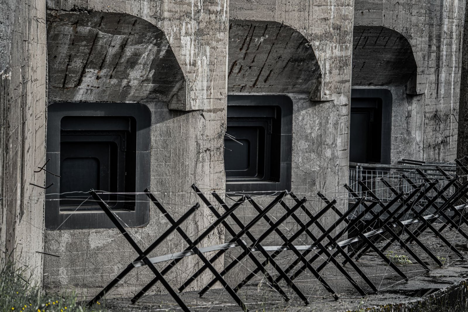 Imagen detallada de una estructura de concreto con cercas metálicas geométricas en un entorno industrial.