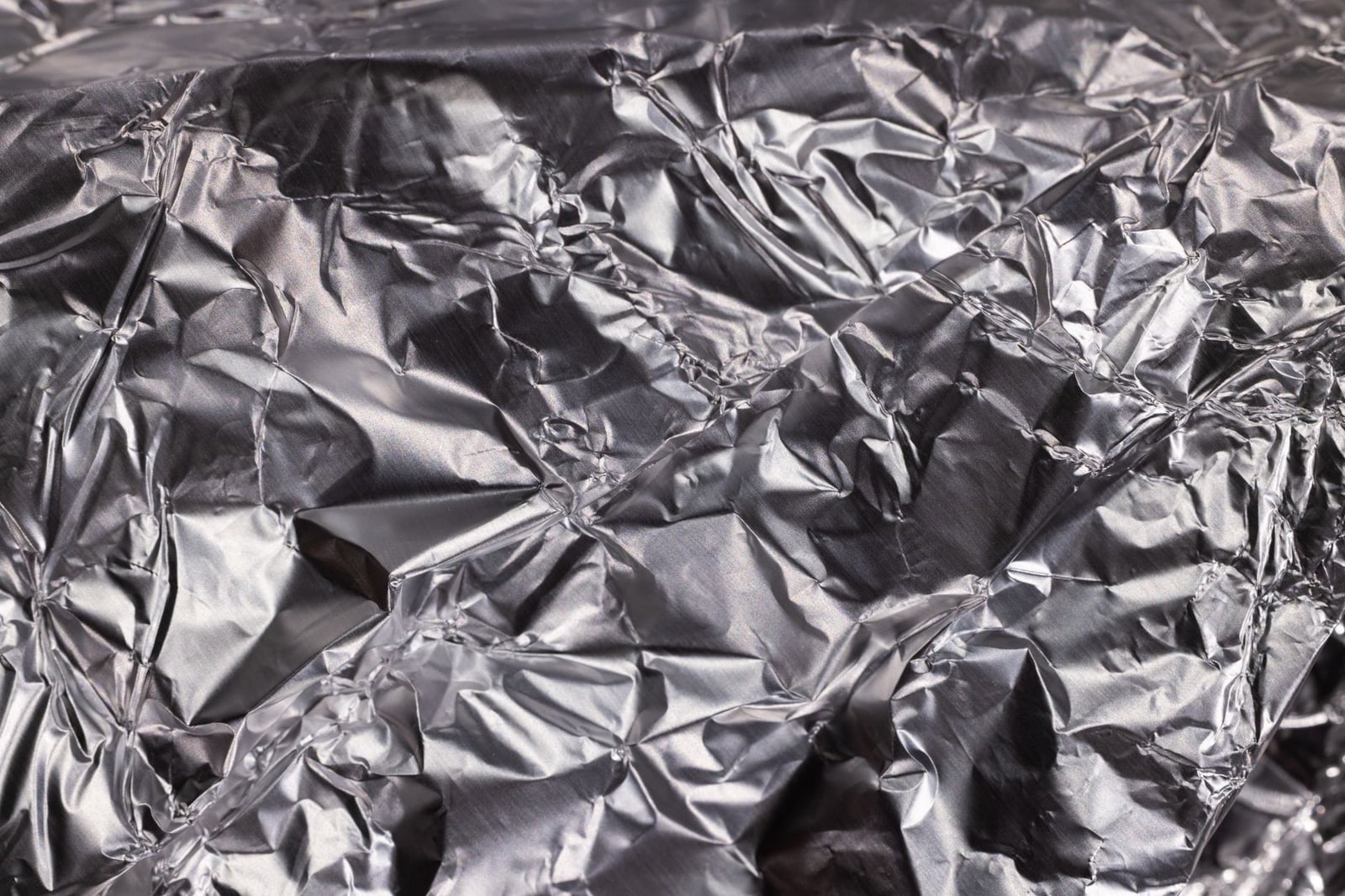Primer plano de papel de aluminio arrugado brillante que muestra una textura metálica arrugada.