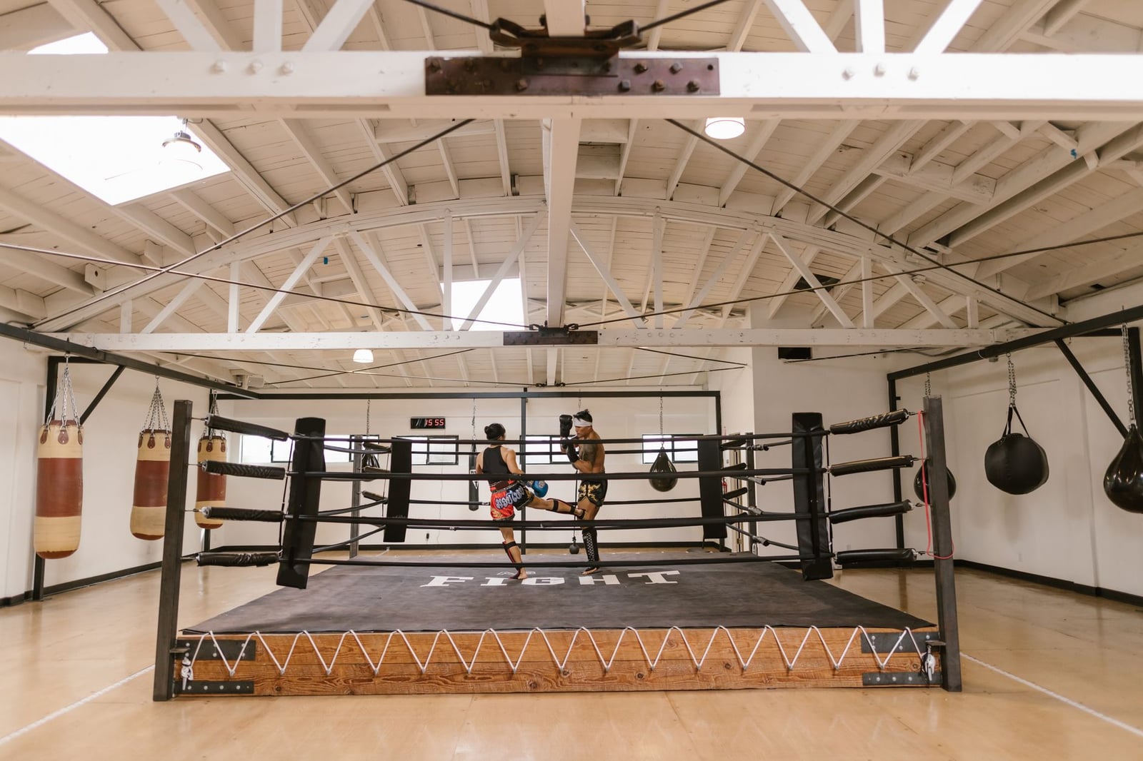 Dos atletas participan en una intensa sesión de sparring en un gimnasio de boxeo bien iluminado.
