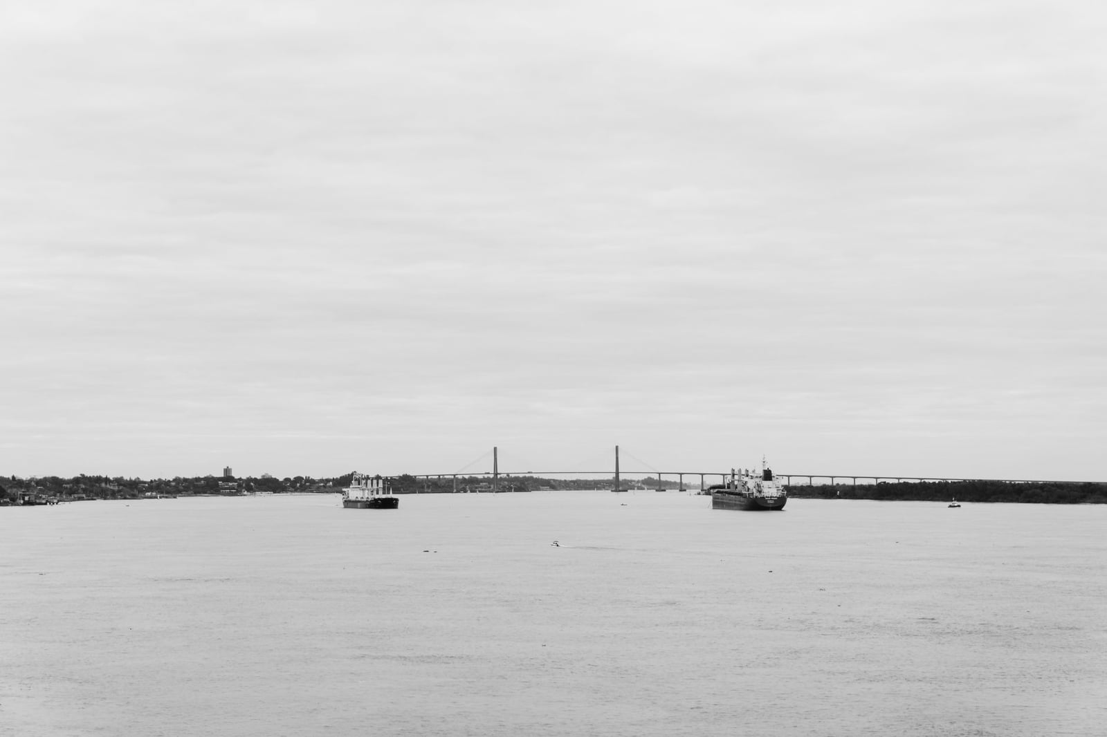 Imagen en blanco y negro de barcos cerca del Puente Rosario-Victoria en el Río Paraná.