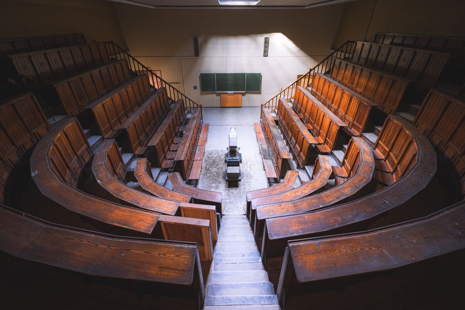 Aula vintage vacía con bancos de madera y pizarra, vista desde arriba.