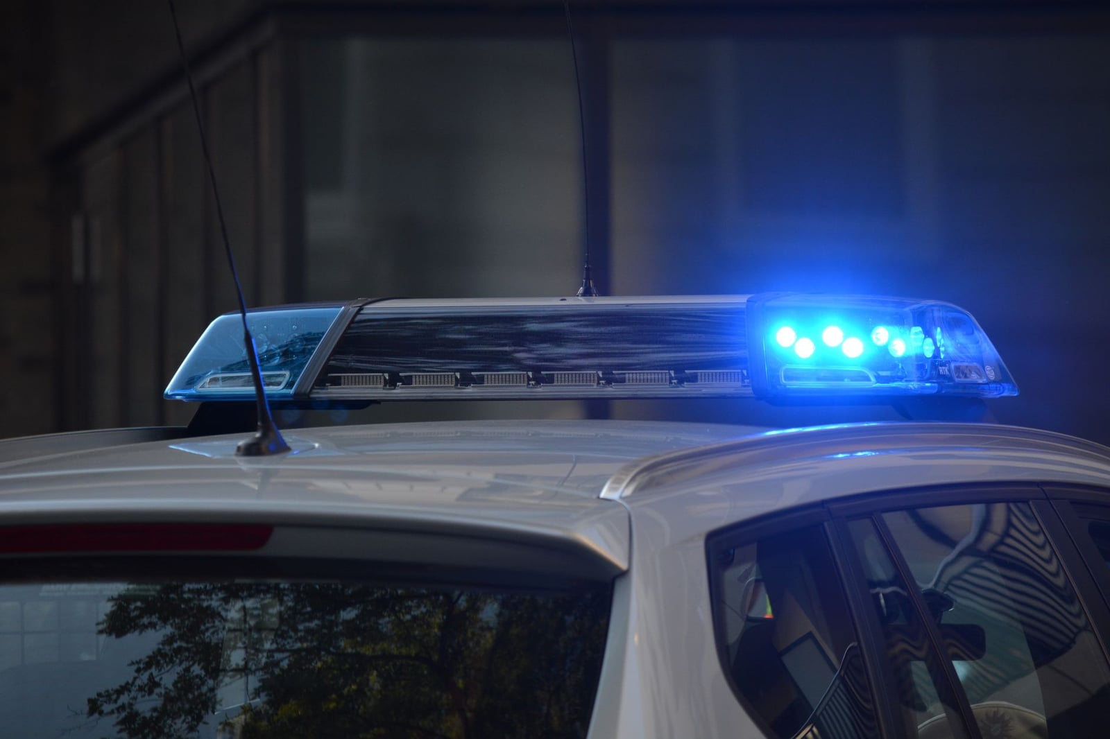 Acercamiento a las luces intermitentes azules de un coche de policía en un entorno urbano.