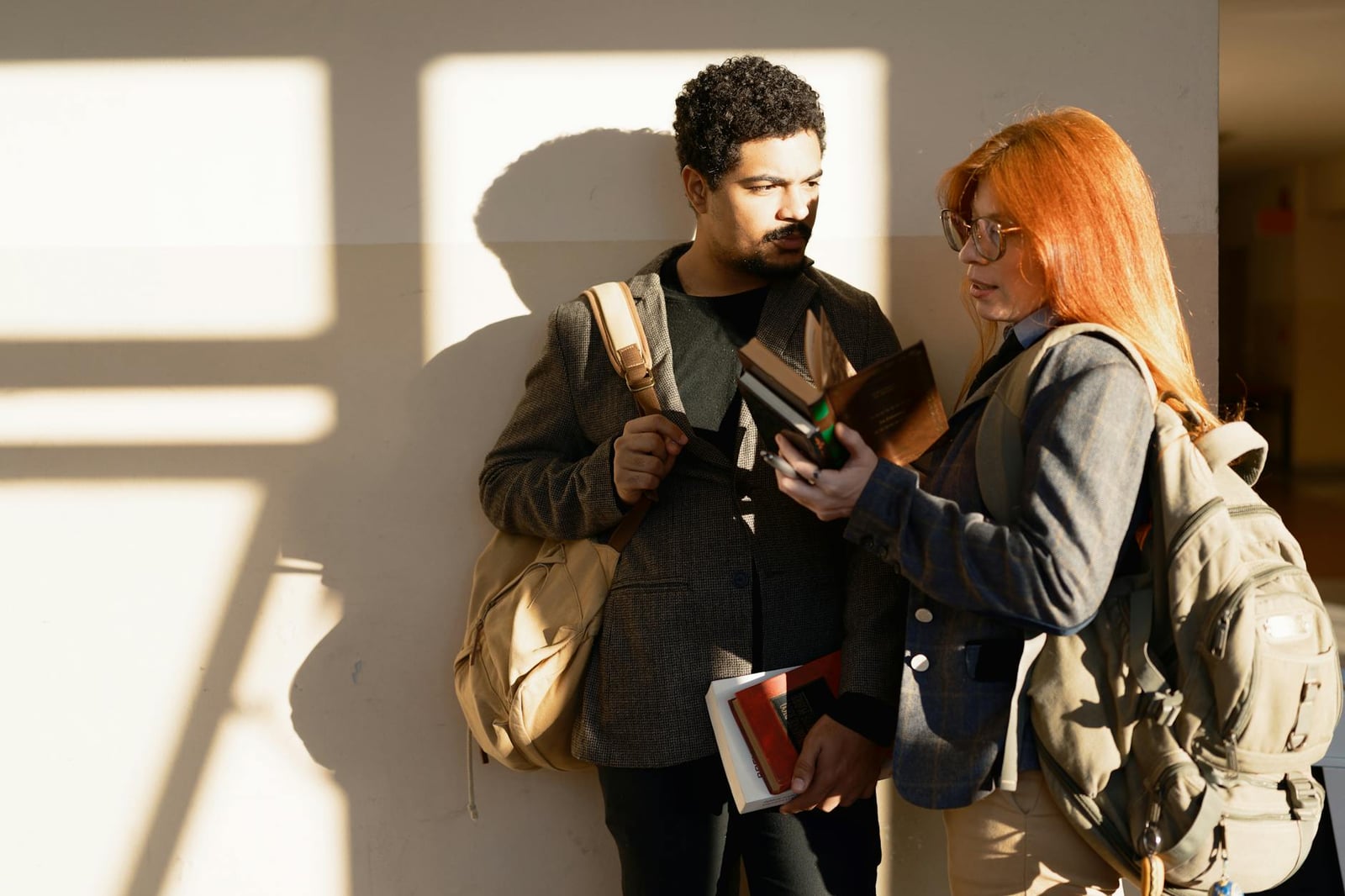 Dos estudiantes conversando sobre un libro en un pasillo soleado del campus de Buenos Aires.