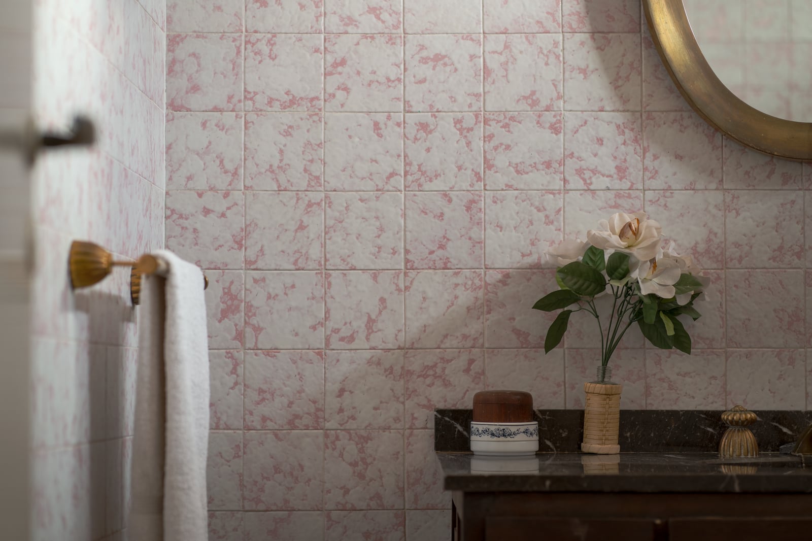 Encantadora escena de baño con azulejos vintage, espejo redondo y decoración floral.