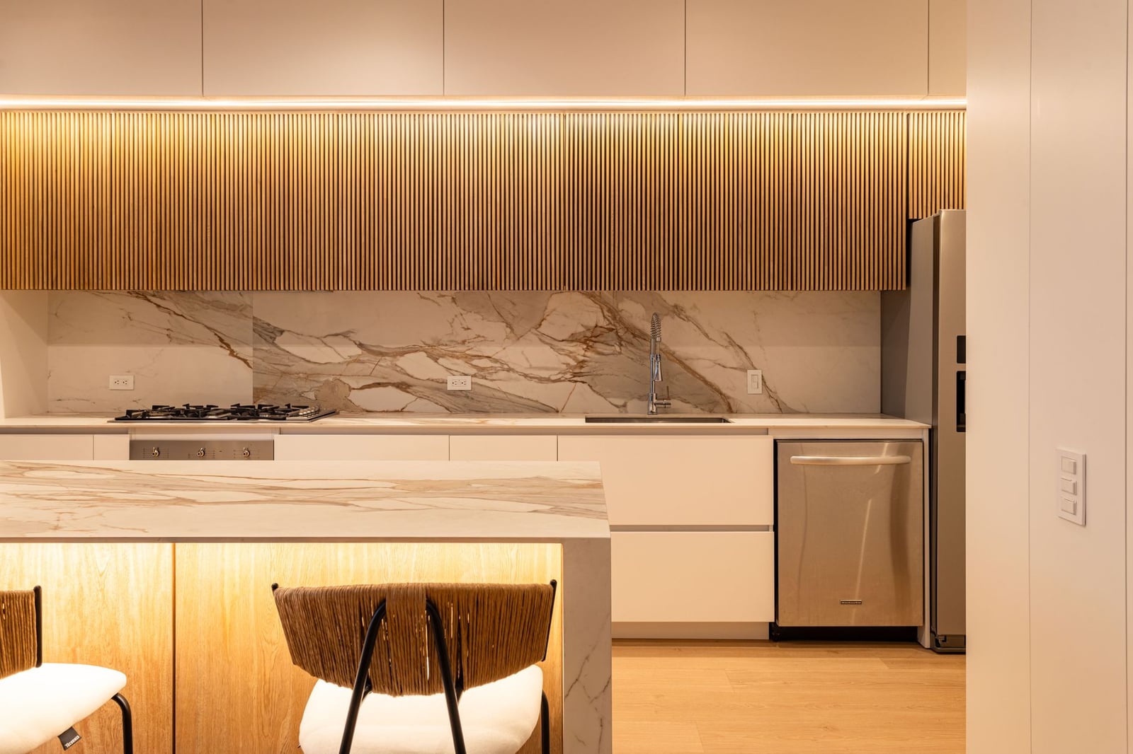Diseño de cocina contemporánea elegante con encimeras de mármol y paneles de madera.