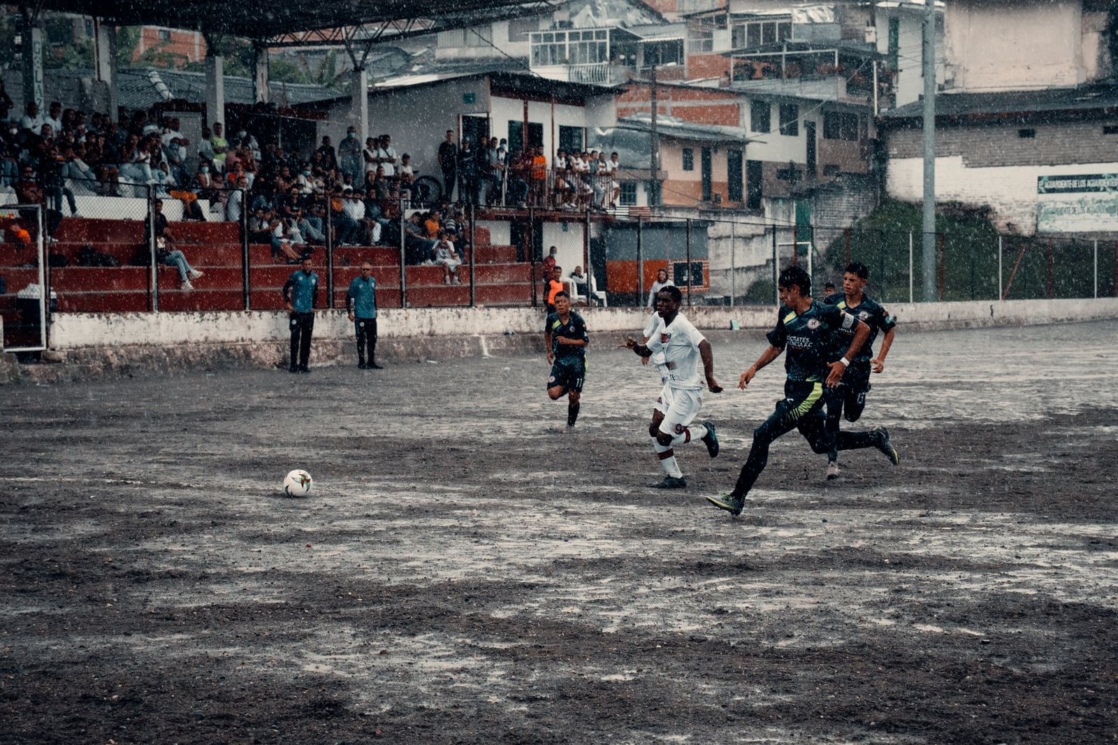 Emocionante partido de fútbol en Neira, Colombia, capturando a los atletas en acción durante un partido lluvioso.