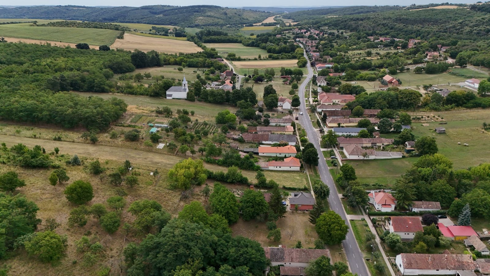 Una vista aérea panorámica de un pueblo europeo y un paisaje rural con campos y árboles.